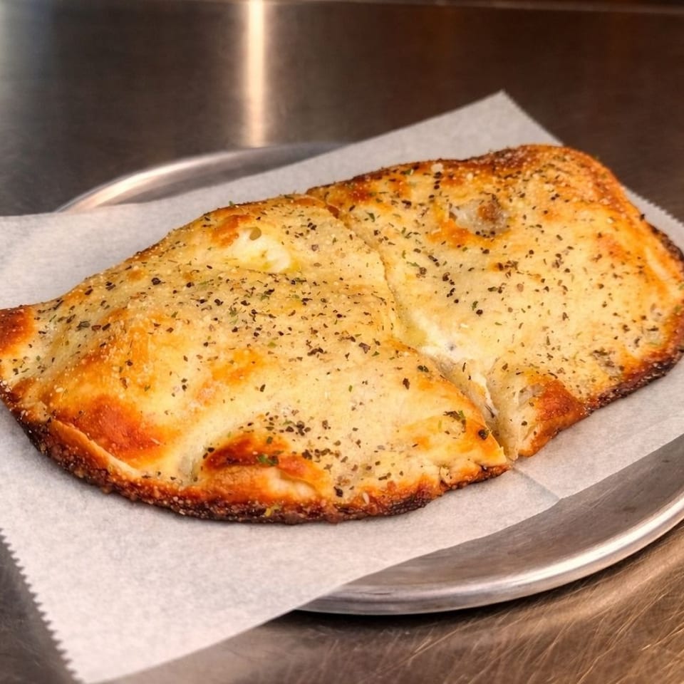 Golden brown calzone with herbs and spices on parchment paper, on a metal tray.
